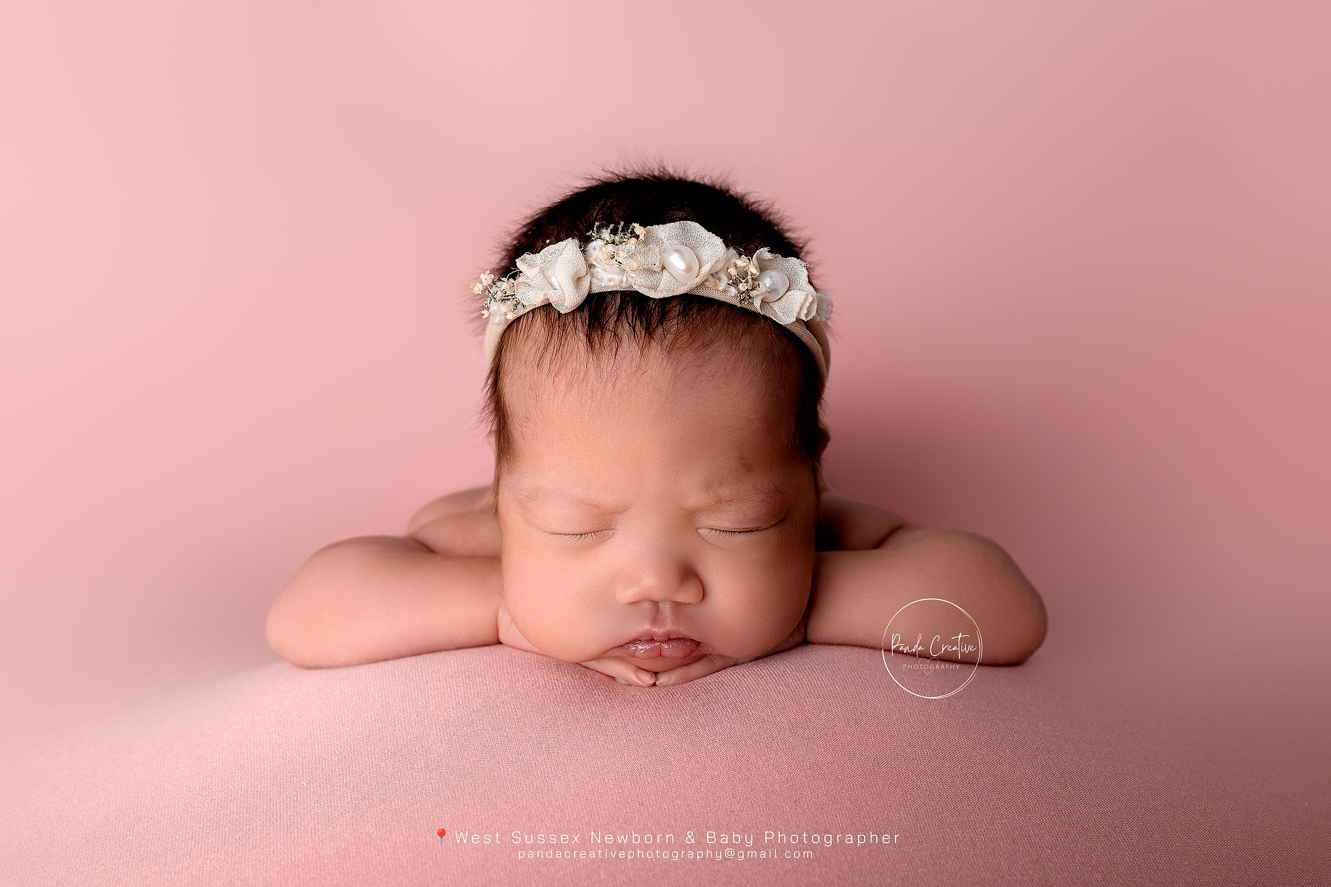 Newborn forward facing pose, baby girl on pink beanbag posing
