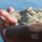 Photo des alliances dans les mains avec du sable et un rayon de soleil