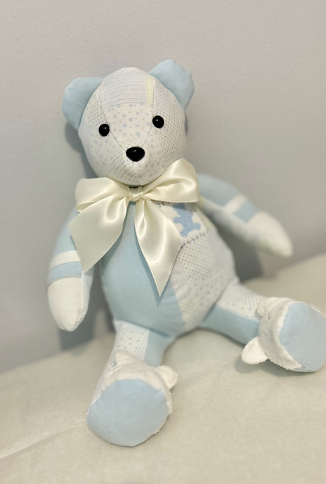 14-inch customizable memory bear handmade from light blue and white sentimental clothing, shown with a satin bow. Includes options for embroidery and up to 8 fabric items, available through Zing Art Studio.