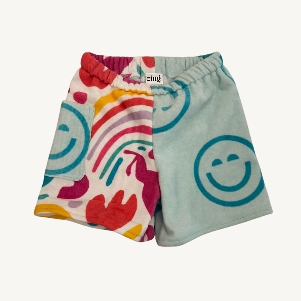 Handmade towel shorts with split-leg design. One side has light blue smiley faces the other has a rainbow unicorn pattern.