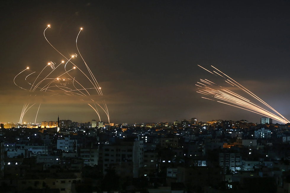 A dramatic photo of rockets released from Gaza on the right and the interceptors from Israel's Iron Dome anti-rocket system on the left, snaking a winding path to meet those rockets