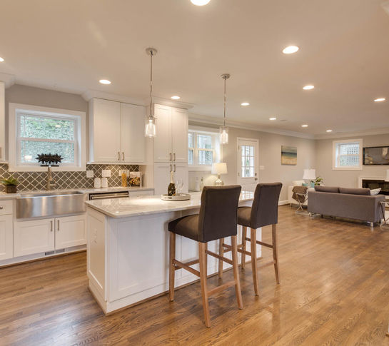 white kitchen view with white cabinets and island with black stools