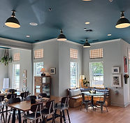 Bright cafe interior with teal ceiling, wooden floors, and seating