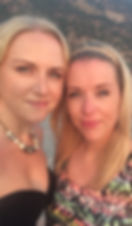 Photo of two blonde women, dressed for a night out with a Mediterranean mountain behind them.