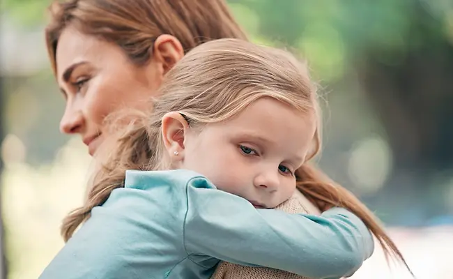 A woman holding a young girl who looks sad.webp