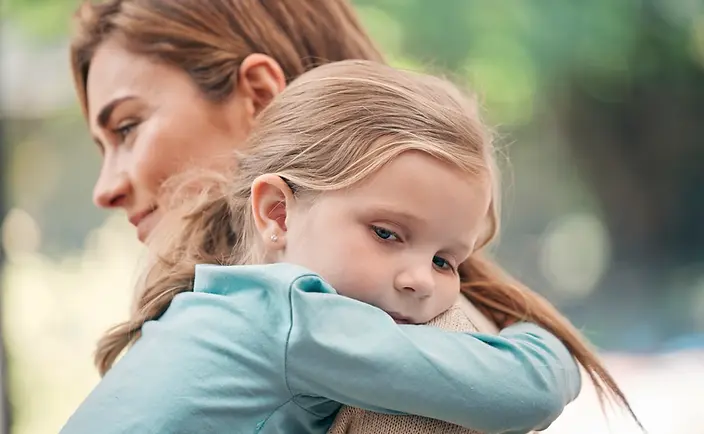 A woman holding a young girl who looks sad.webp