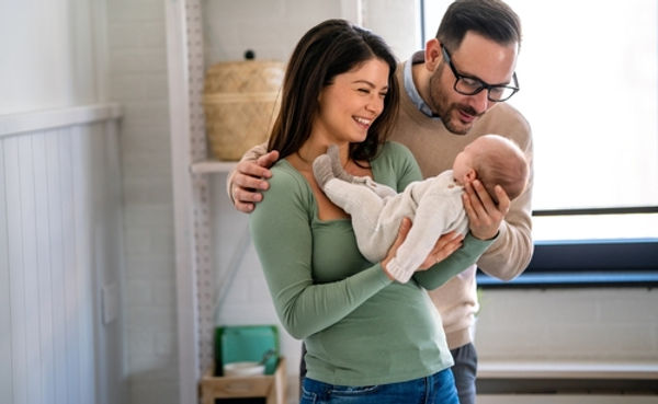 Happy couple holding a newborn after receiving help from an adoption lawyer Arkansas trust