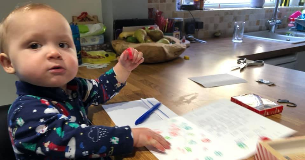 a toddler decorating a christmas card with stamps