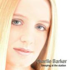 The front album cover of Charlie Barker's Sleeping at the Station album. A headshot of Charlie with bright blonde hair and green eyes, looking directly at the camera, on a white background.