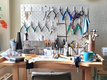 Jeweller’s workbench with tools, metal sheets and materials ready for making.