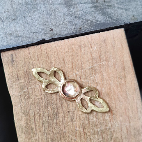 Brass leaf setting on the bench pin after overheating — showing the metal’s reaction to too much heat.