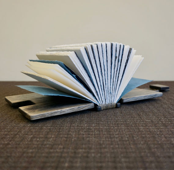 A handmade aged oak open notebook with deckled pages.