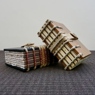 Handmade Iroko wood books with exposed spine sewings on raised hemp rope supports made by a book artist using medieval book binding techniques.