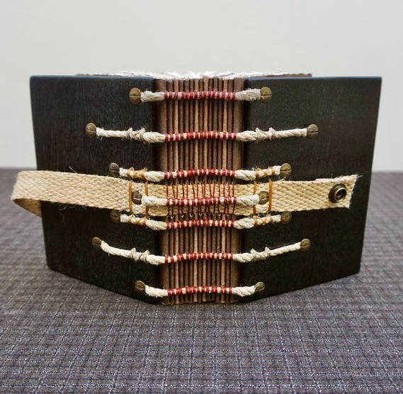 A handmade Iroko wood notebook with a beautiful binding on exposed hemp rope supports.