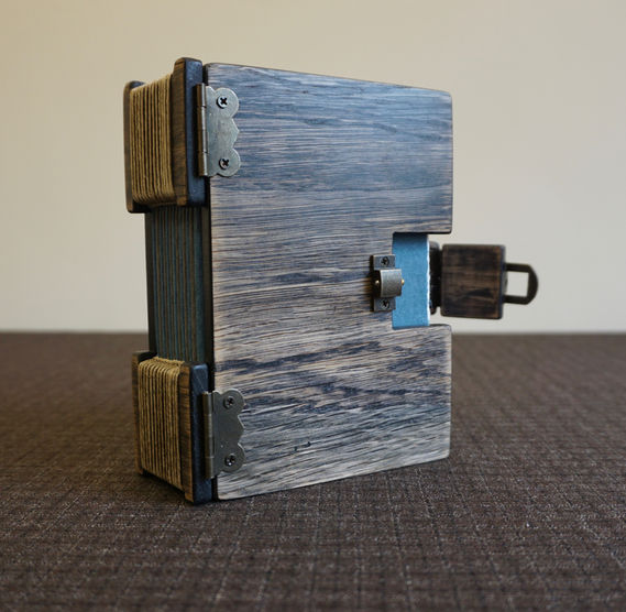 A handmade aged oak notebook with a brass clasp and buttonhole stitch binding.