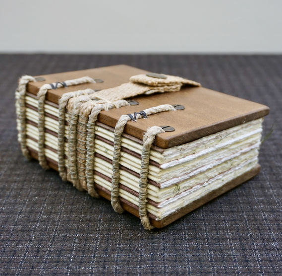 A handmade Iroko wood notebook with a beautiful exposed spine sewing on hemp rope supports.