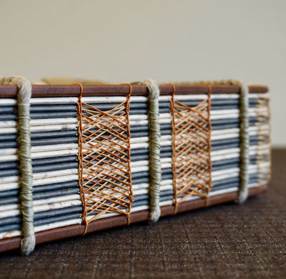 A handmade mahogany book and sketching journal showing the decorative Celtic weave sewing across the spine of the book.