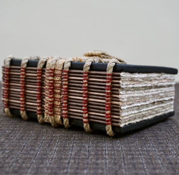 A handmade Iroko wood notebook with a beautiful exposed spine sewing on hemp rope supports.