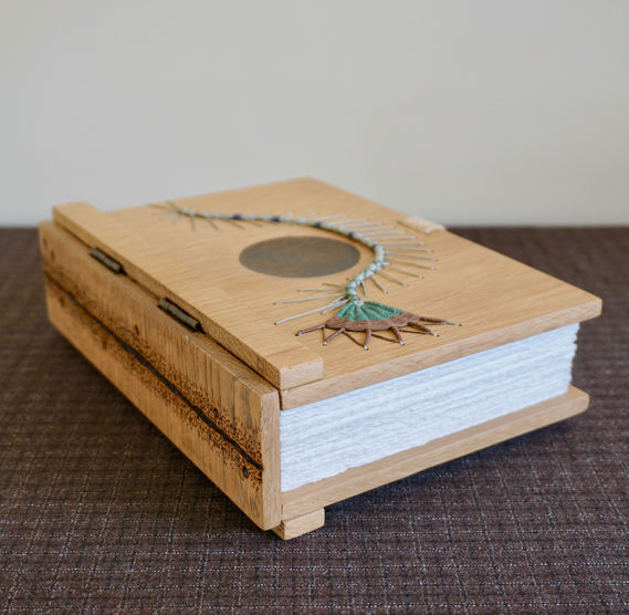 A handmade oak book and journal with hinged spine decorated with pyrography.