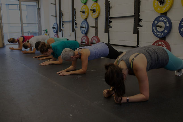 Women doing plank exercise during small group strength training session