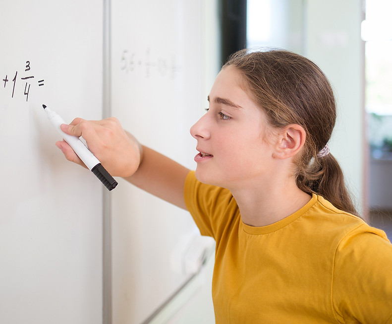 Student in yellow shirt solving problem at white board