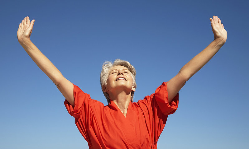 Happy & Healthy woman raising her arms to a beautiful blue sky