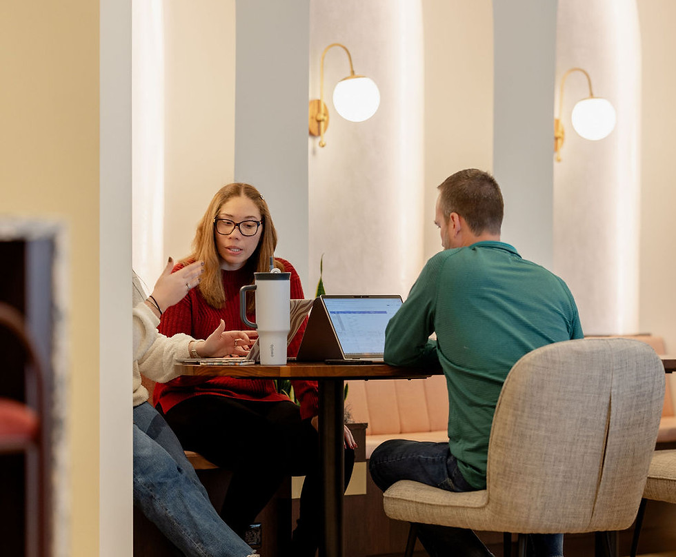 Three people at a table in a modern cafe with arched niches and warm lighting at The Commons 150 Fayetteville