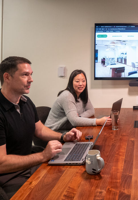 A group of colleagues working at a conference table with TV screen at The Commons