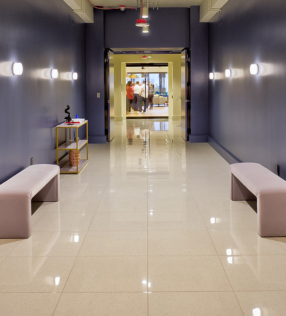 Entrance hallway to The Commons 150 with blue walls, benches, and lights leading to an open common area