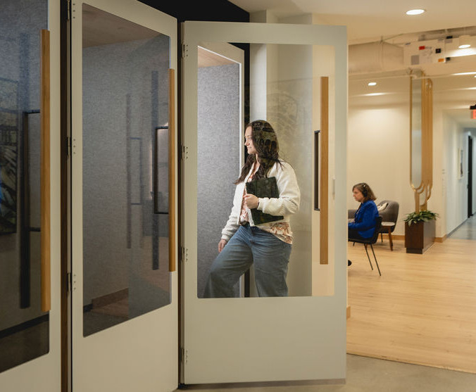 Woman entering a private phone booth with another person seated in the commone area at The Commons 150 Fayetteville