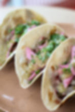 Uno Más Taqueria tacos with shredded meat, pickled onions, tomatillo salsa, and cilantro on a beige plate in Buckhead Atlanta