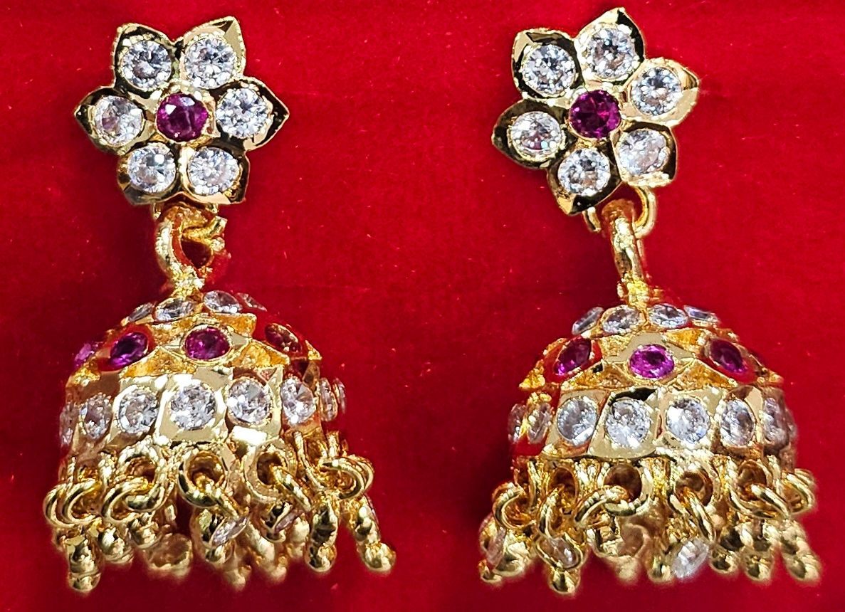 Golden earrings with diamonds and rubies on a red background. JeJo Stores