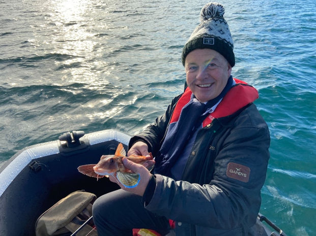angler holding fish in a small boat