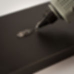 Bico de pistola aplicando Hot Melt transparente numa peça de madeira preta