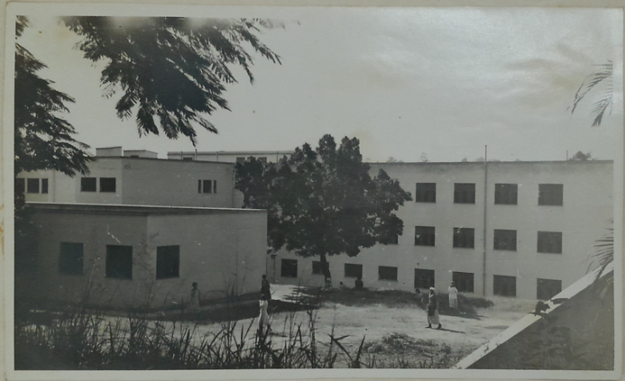 Prédio com quatro andares e muitas janelas gradeadas. À esquerda, uma construção pequena. Ao centro, em frente ao prédio, uma arvore e pacientes transitando.