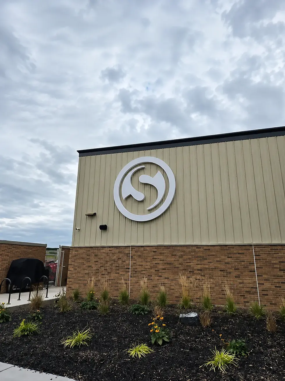 Custom illuminated circular logo sign installed on the exterior wall of a public park building