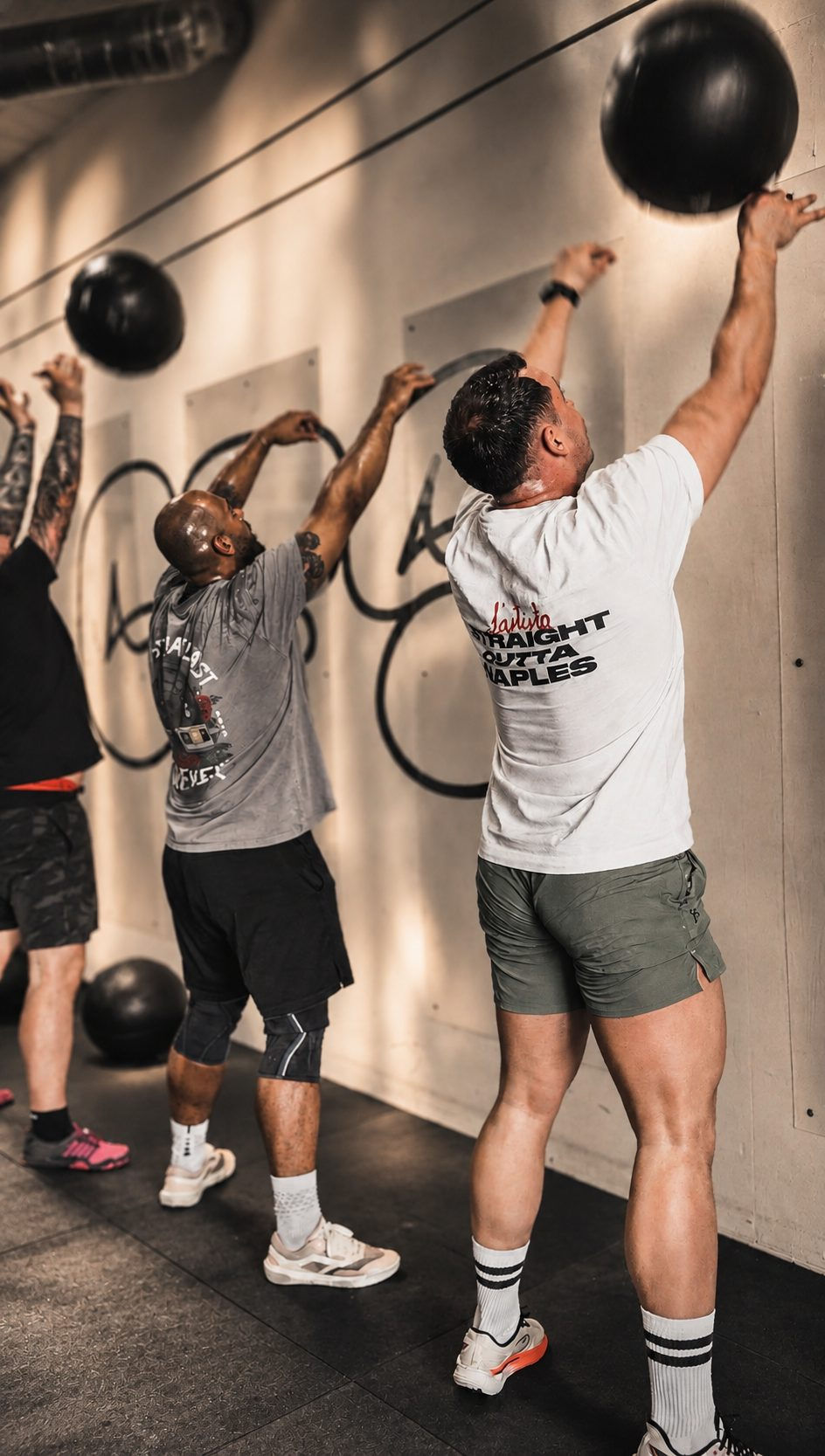 Athletes throwing wall balls against a target wall during a HYROX session