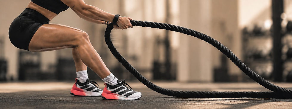 Athlete in a low squat working battle ropes on the gym floor