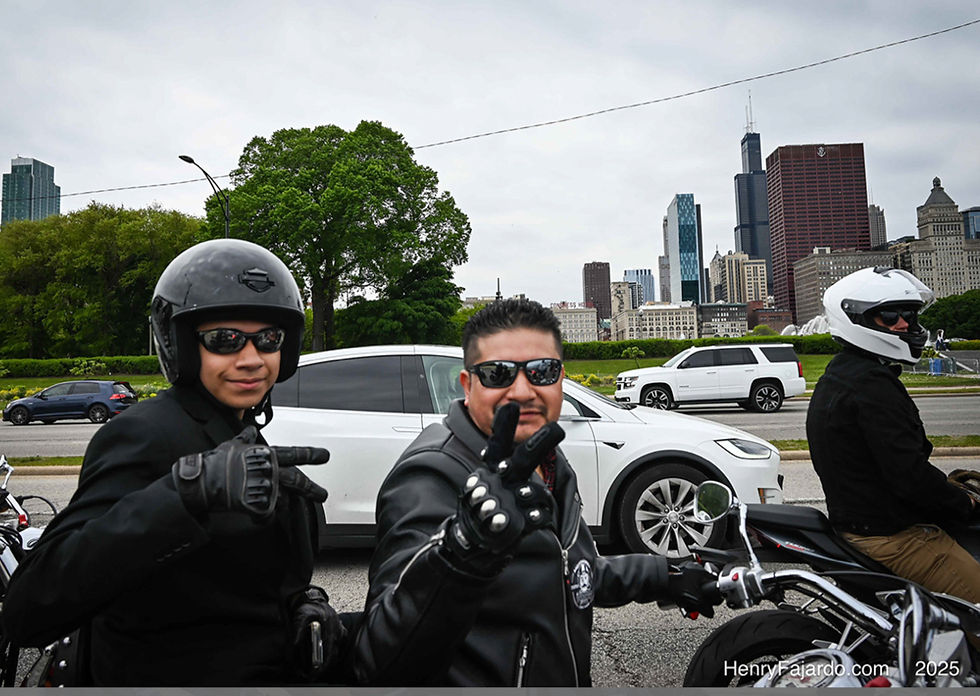 Two motorcyclists, one points, one makes peace sign, city