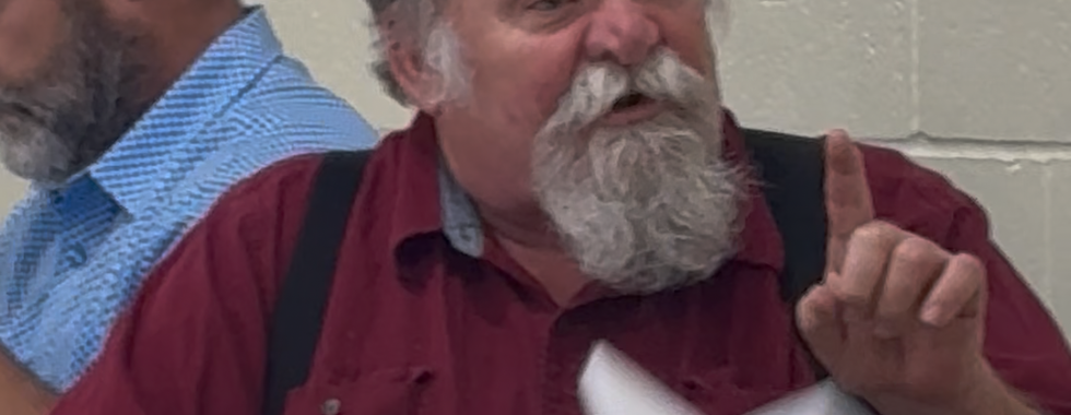 Steve McDonald, alderman in Silex, gestures while speaking at a table during a board of aldermen meeting with documents and a gavel in front of him.