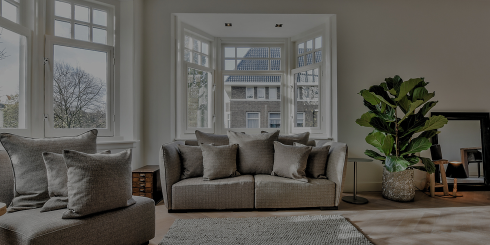 Modern living room with gray sofas, large bay windows, a potted fiddle-leaf fig, and a calm, airy feel