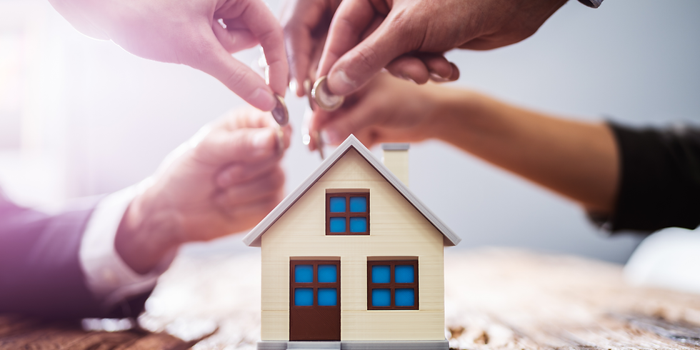 Hands stacking coins above a small model house, symbolizing home saving or investment in a bright, blurred setting