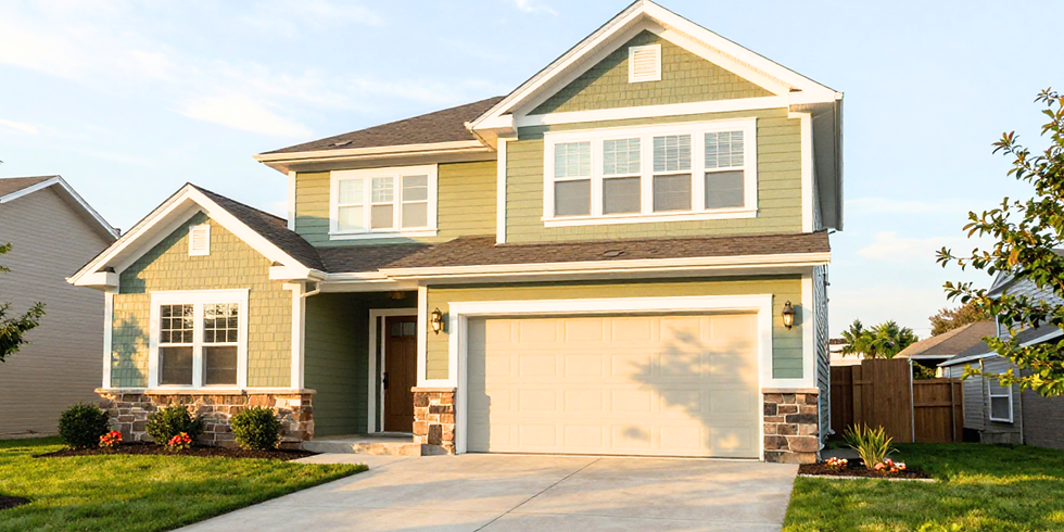 Sunlit green two-story suburban house with white trim, garage, driveway, and manicured lawn at dusk.