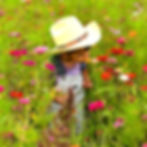 Little boy in a straw hat smelling wildflowers