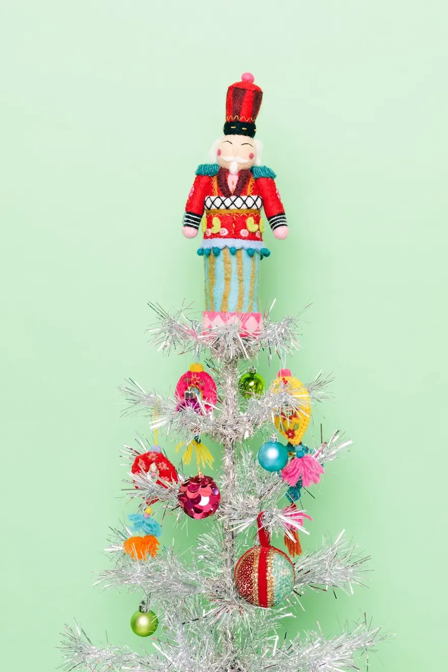 Hand-felted and embroidered Nutcracker at top of tree