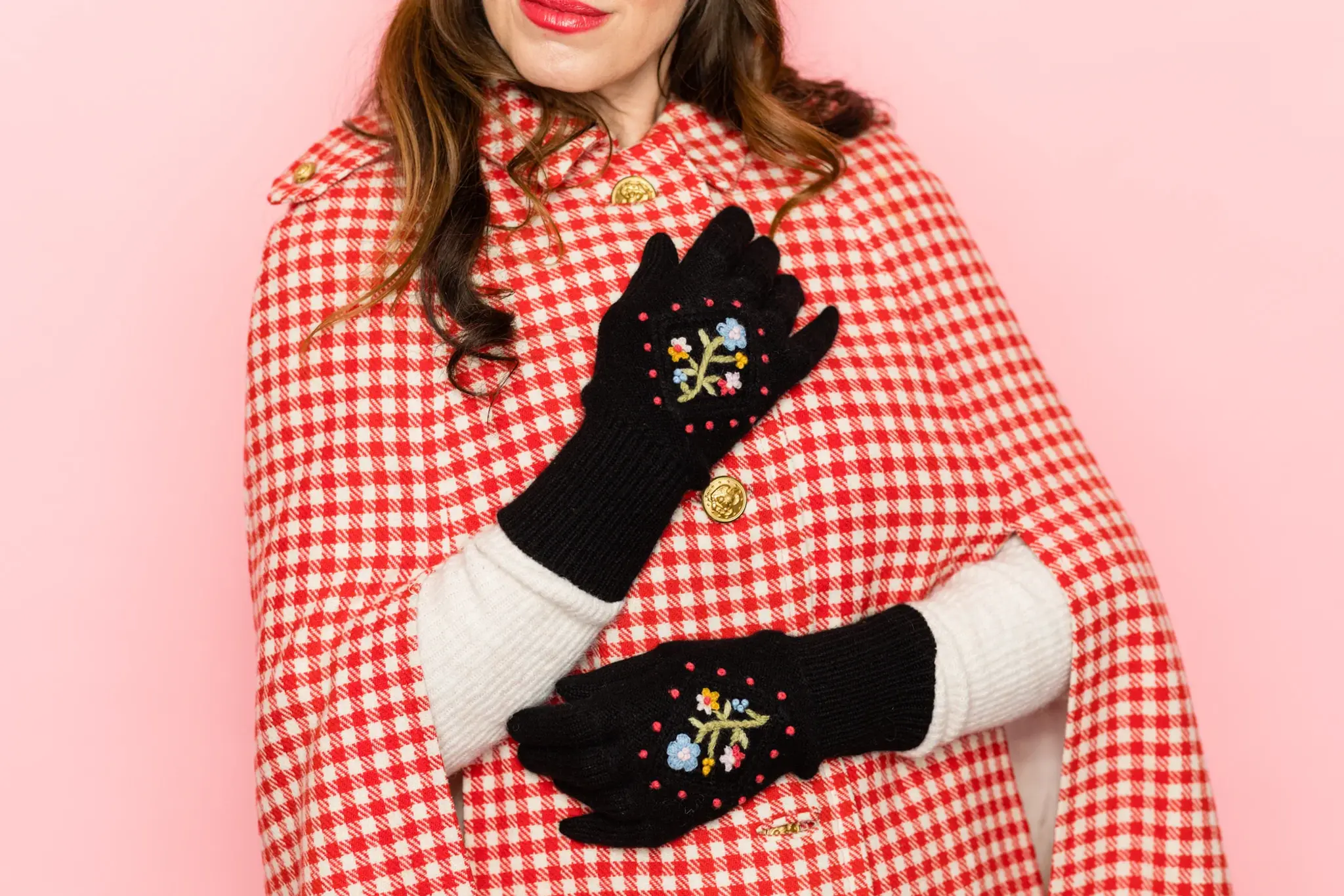 Woman in red coat wearing black embroidered gloves