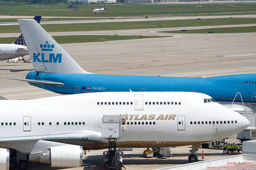 Atlas Air Boeing 747-400 N322SG Houston Express. Cleaning crew hides from sun under jet bridge. KLM 747. Colgan Air Saab 340 ready to land on runway 26L at Houston Intercontinental Airport IAH operating for United Express.