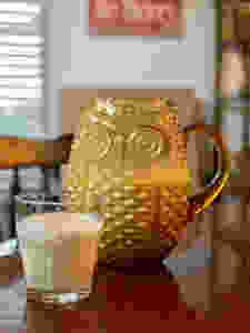 Yellow glass owl pitcher and glass of coquito on a table