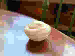Very light pink whipped cream in a small glass bowl on a wooden table.