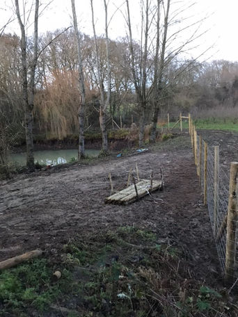 Fishery security fence being erected with 6ft metal wire and 9ft timber stakes